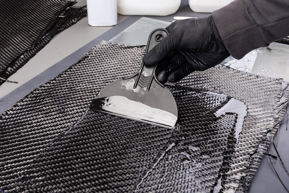 hand,working,epoxy,resin,into,woven,carbon,fiber,reinforcement,cloth.
